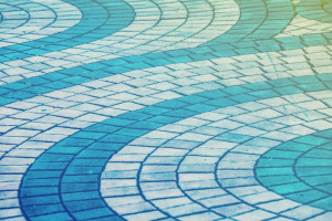 Curved pattern of cobblestone pavement with a gradient of blue to turquoise color overlay.