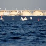 A large lng (liquefied natural gas) tanker ship at sea, viewed from over a body of water with bold "lng" lettering visible.