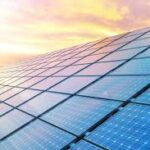 Solar panels under a colorful sunset sky.