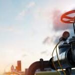 Industrial pipeline with valve against sky.